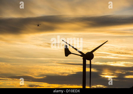 Un ultraleggero vola passato una turbina eolica su Kirkstone Pass, Lake District, Cumbria, Regno Unito al tramonto. Foto Stock