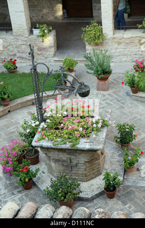 Bene con i fiori del vecchio convento francescano in Assisi Foto Stock