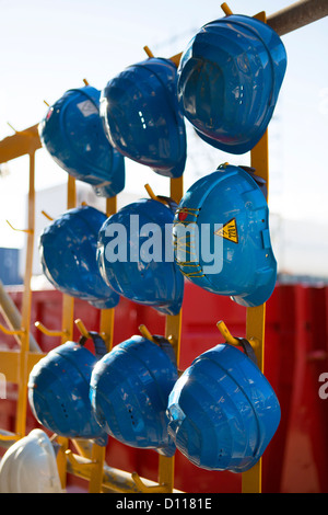 Blue hardhats appeso sul sito di costruzione. Foto Stock