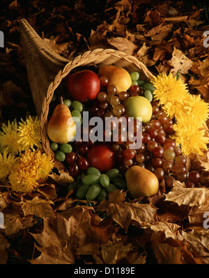 Negli anni settanta il clacson di vimini di un sacco riempito con frutta mele pere uva nella parte superiore di foglie di autunno Foto Stock