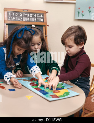 Anni Settanta BOY ragazze i bimbi a mettere insieme PUZZLE DI STATI UNITI KINDERGARTEN DAY CARE Foto Stock