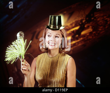 Anni sessanta GIOVANE DONNA BIONDA PARTY HAT NOISEMAKER HORN SORRIDENTE ANNO NUOVO sfondo orologio Foto Stock