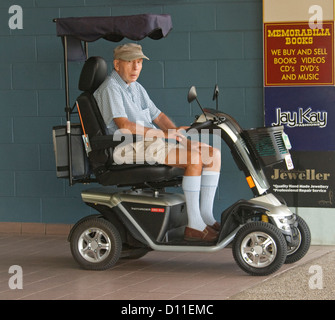 Uomo anziano - pensionato - sulla mobilità elettrica scooter sul marciapiede della città in Australia Foto Stock