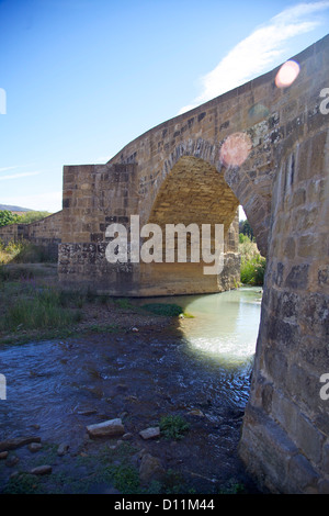 Un ponte di pietra e un bagliore di sole, un luogo ombreggiato lungo la strada francese del cammino di Santiago di Compostela Foto Stock