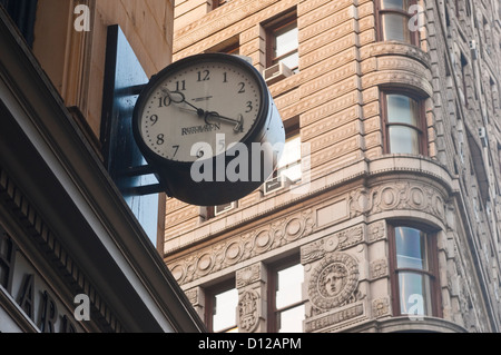 Orologio contro il Fuller Building nel quartiere Flatiron di Ne York Foto Stock