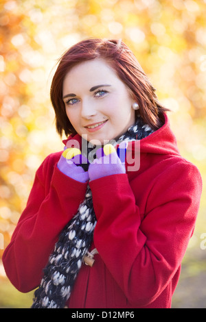 Giovane donna che indossa un cappotto rosso in un parco in Scozia. Foto Stock