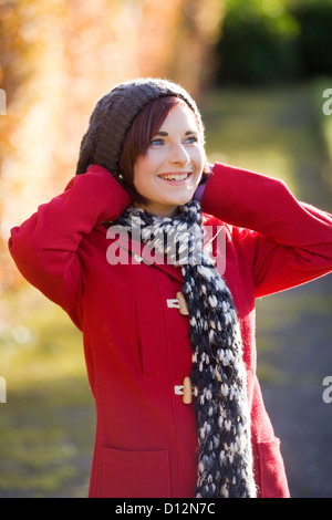 Giovane donna che indossa un cappotto rosso in un parco in Scozia. Foto Stock