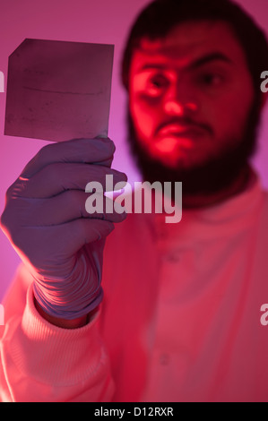 Maschio asiatici scienziato, tecnico o un ricercatore esamina una diapositiva di DNA dalla luce a infrarossi in camera oscura Foto Stock