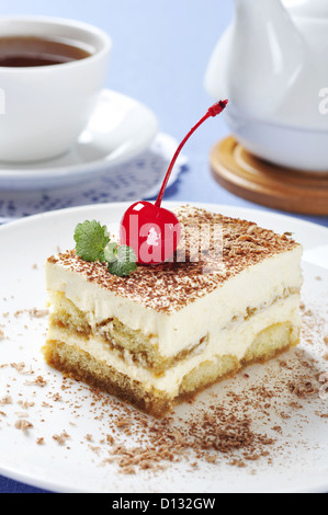 Il tiramisù - Classico dolce con il caffè sulla piastra bianca. Guarnito con ciliegia e menta. Foto Stock