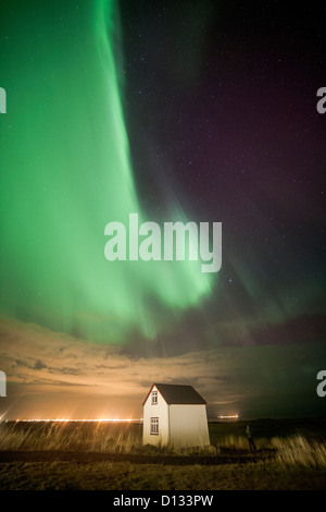 Striature verde dell'Aurora Boreale luci del nord su una piccola casa in un campo in Islanda Foto Stock