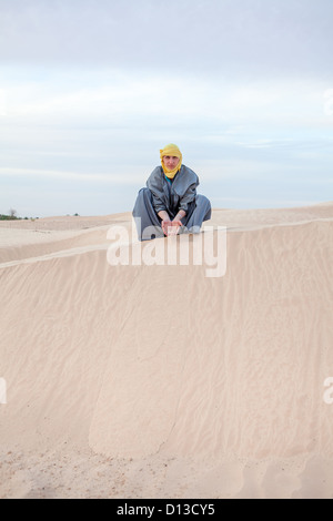 Maschio caucasico nella protezione abiti orientali versando la sabbia con le mani sulle dune del deserto di spazio di copia Foto Stock