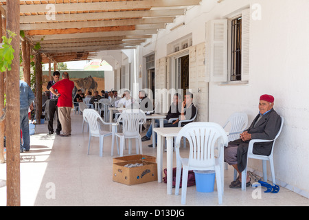 La popolazione maschile è seduta in corrispondenza di un bordo strada cafe durante la siesta, Tunisia, Africa Foto Stock