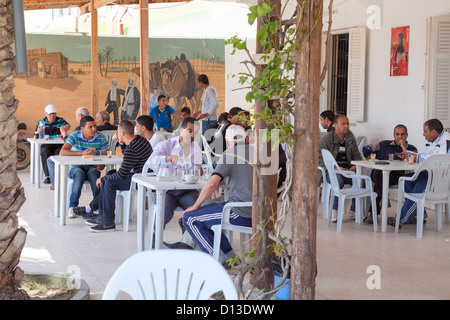 Della popolazione maschile è seduta in corrispondenza di un bordo strada cafe durante la siesta, Tunisia, Africa Foto Stock