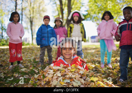 Nuovo Multi-Ethnic canadese di bambini che giocano in foglie di autunno fuori scuola Esl; Guelph Ontario Canada Foto Stock
