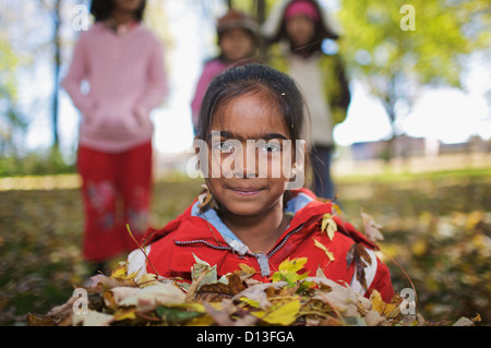 Nuovo Multi-Ethnic canadese di bambini che giocano in foglie di autunno fuori scuola Esl; Guelph Ontario Canada Foto Stock