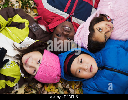 Multi-Ethnic nuovi bambini canadesi giacente in foglie di autunno fuori scuola Esl; Guelph Ontario Canada Foto Stock