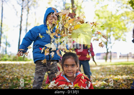 Nuovo Multi-Ethnic canadese di bambini che giocano in foglie di autunno fuori scuola Esl; Guelph Ontario Canada Foto Stock