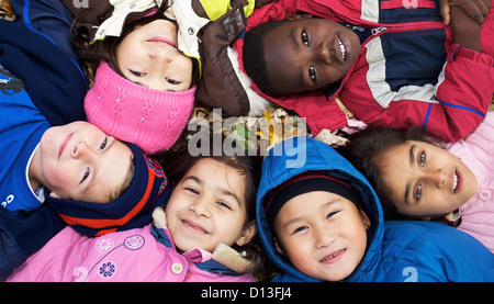 Multi-Ethnic nuovi bambini canadesi giacente in foglie di autunno fuori scuola Esl; Guelph Ontario Canada Foto Stock