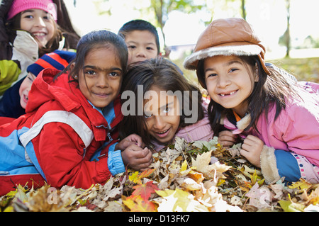 Nuovo Multi-Ethnic canadese di bambini che giocano in foglie di autunno fuori scuola Esl; Guelph Ontario Canada Foto Stock