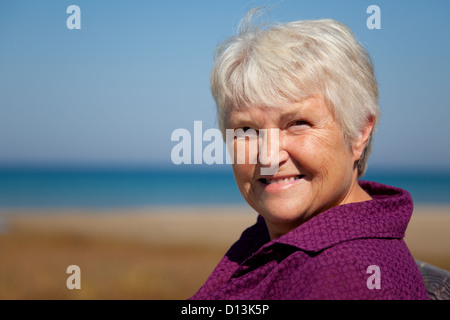 Un senior donna, testa e spalle shot, sorridente alla fotocamera. Foto Stock