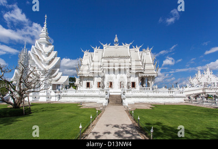 Wat Rong Khun, o bianco tempio, Chaing Rai, Thailandia del Nord - Vista laterale su una luminosa giornata soleggiata con un cielo blu chiaro Foto Stock