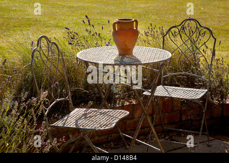 Metallo stile francese di mobili da giardino Tavolo e sedie con vaso in terracotta in estate il giardino inglese Foto Stock