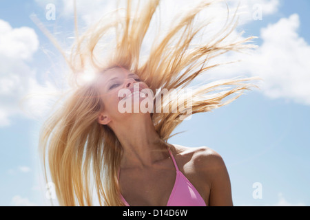 Donna sorridente nel lanciare i suoi capelli Foto Stock