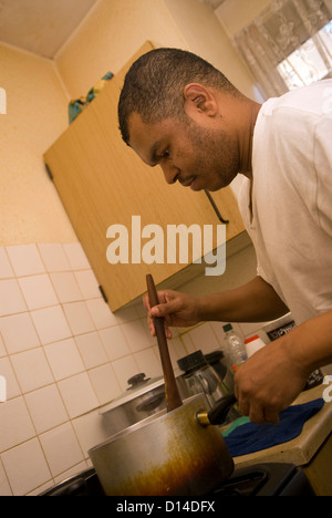 Il marito che si prende cura di sua moglie disabili a casa a preparare il pranzo per loro sia in cucina, Londra, Regno Unito. Modello rilasciato immagine (MR). Foto Stock