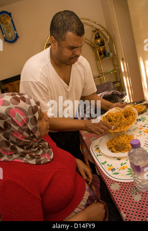 Il marito che si prende cura di sua moglie disabili (amputazione della gamba) a casa che serve il suo pranzo, Londra, Regno Unito. Modello rilasciato (MR) immagine. Foto Stock