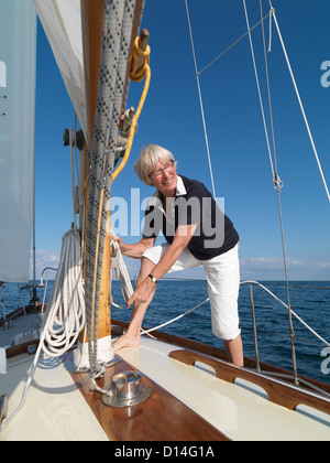 Donna di manovre di regolazione sulla barca a vela Foto Stock