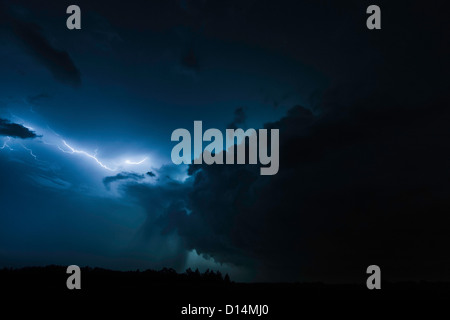 Nuvole di illuminazione oltre il paesaggio rurale Foto Stock