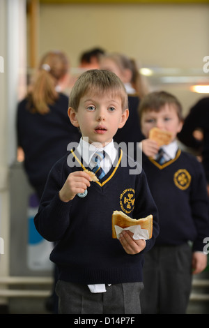Uno scolaro mangiare toast dopo mattina insieme alla Madonna e San Werburgh Cattolico della scuola primaria a Newcastle-under-Lyme, St Foto Stock