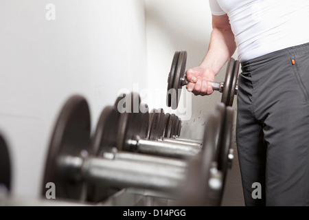 L'uomo utilizzando pesi liberi in palestra Foto Stock