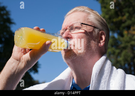 Uomo più anziano di bere succo di arancia all'aperto Foto Stock