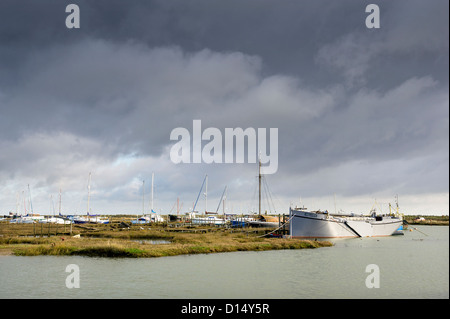 Barche ormeggiate sui mudberti nell'atmosfera di Tollesbury Laltings in Essex. Foto Stock