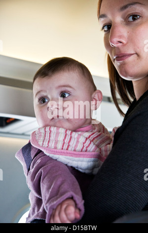 Giovane madre holding baby boy procede alla sua sede per il decollo di Aeromexico Connect volo tra Città del Messico e Huatulco Foto Stock