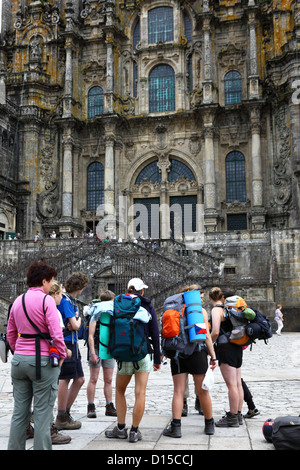 Gli escursionisti terminano la strada di San Giacomo di fronte alla cattedrale, Praza do Obradoiro / Plaza del Obradoiro, Santiago de Compostela , Galizia , Spagna Foto Stock