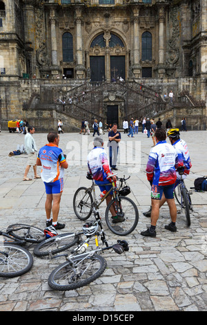 I ciclisti terminano la strada di San Giacomo di fronte alla cattedrale, Praza do Obradoiro / Plaza del Obradoiro, Santiago de Compostela , Galizia , Spagna Foto Stock