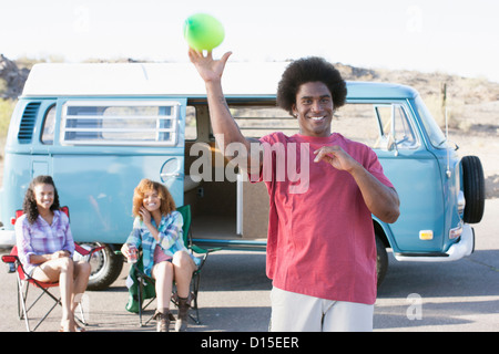 Uomo sorridente e donne davanti a van Foto Stock