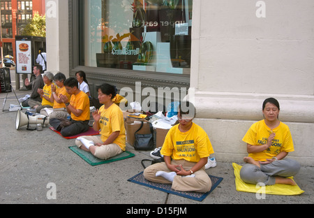 Un BUDDDHIST RISPOSTA ALLA GUERRA - Falun Gong (Falun Dafa) mediano nell'angolo di Houston Street e Broadway a New York City Foto Stock