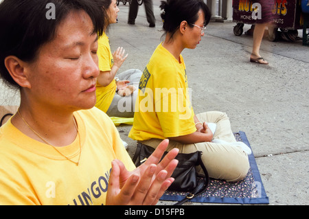 Un BUDDDHIST RISPOSTA ALLA GUERRA - Falun Gong (Falun Dafa) mediano nell'angolo di Houston Street e Broadway a New York City Foto Stock