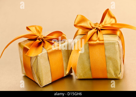 Due confezioni regalo in oro carta di avvolgimento con nastro e prua Foto Stock