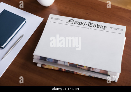 Una pila di quotidiani con il titolo 'News di oggi e di spazio vuoto per informazioni giacente sul desktop di Office. Foto Stock