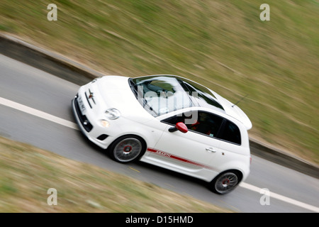 Un moderno e bianco Abarth Fiat 500 car guida veloce lungo una strada. Foto Stock