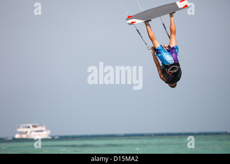 Kiteboarder navigare in acque blu e salti in aria in alto. Foto Stock