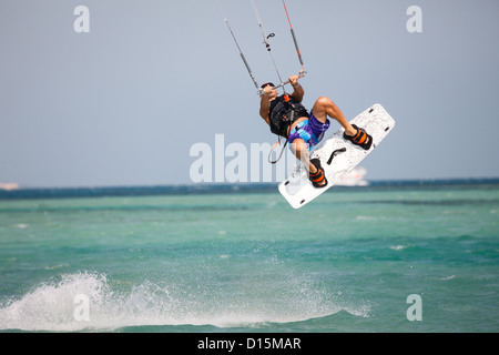 Kiteboarder navigare in acque blu e salti in aria in alto. Foto Stock