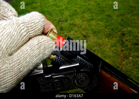 La mano in maglia di lana guanto senza dita 28 caricamento fucile calibro di cartuccia della shell nella camera Foto Stock