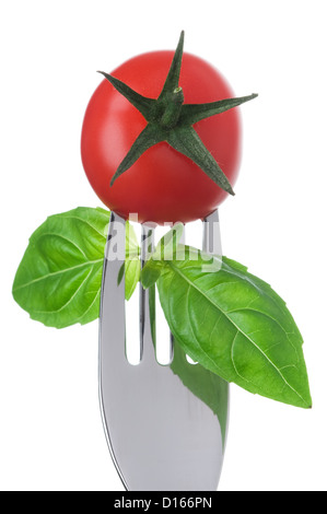 Cherry pomodoro e basilico foglie su una forcella isolata contro uno sfondo bianco Foto Stock