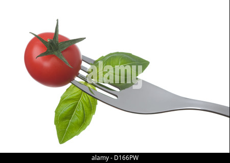 Cherry pomodoro e basilico foglie su una forcella isolata contro uno sfondo bianco Foto Stock