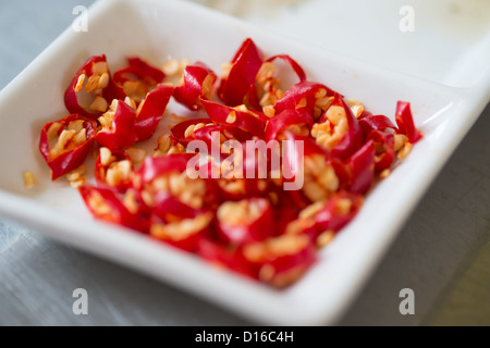 Tagliate a fette peperoncini rossi in un vaso di ceramica Foto Stock